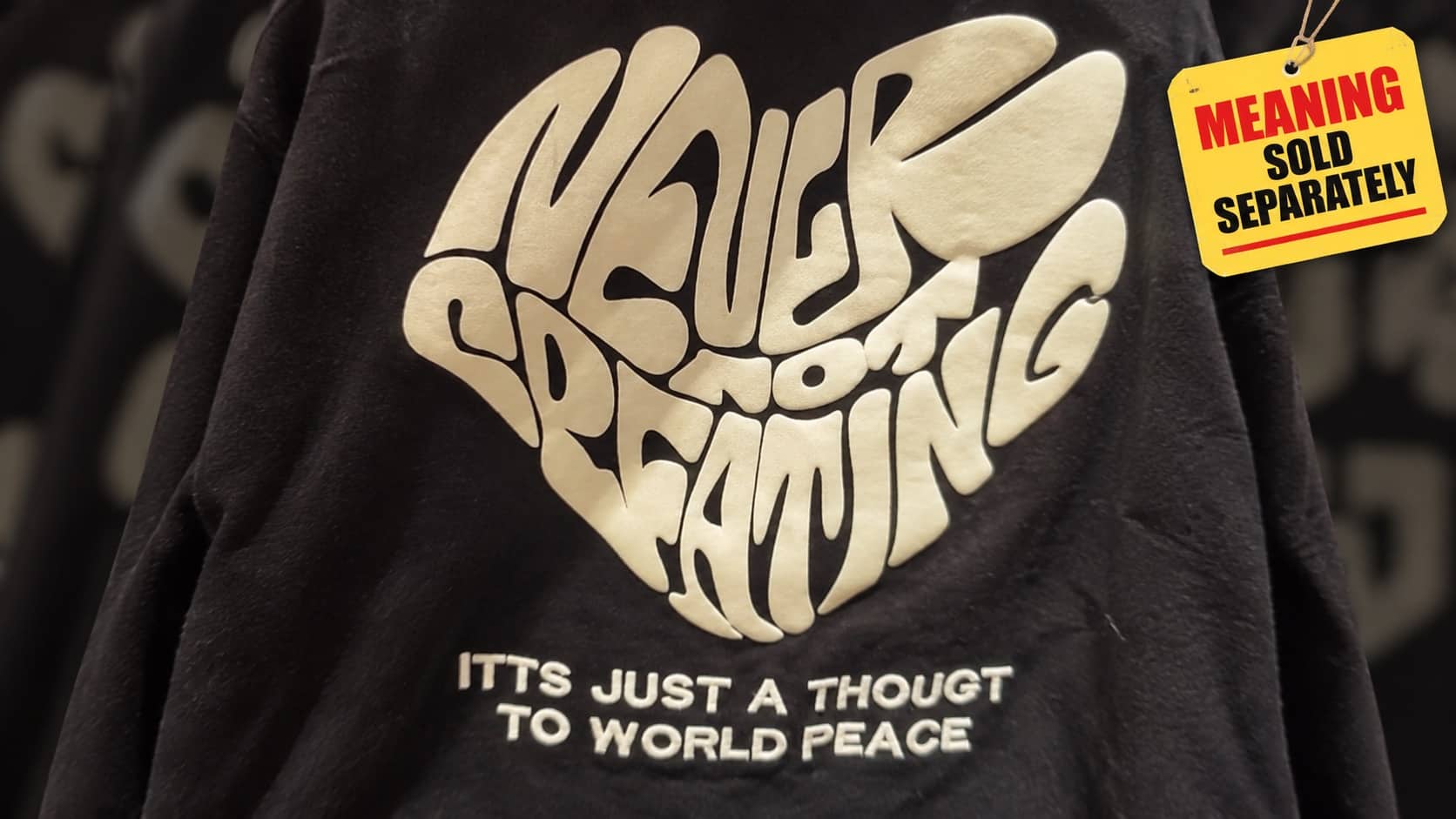 Black sweatshirt with scrambled text and a poorly translated inspirational quote about world peace.