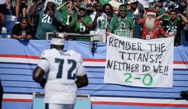 Eagles fans in the stands holding a misspelled Remember the Titans sign celebrating a 2-0 start