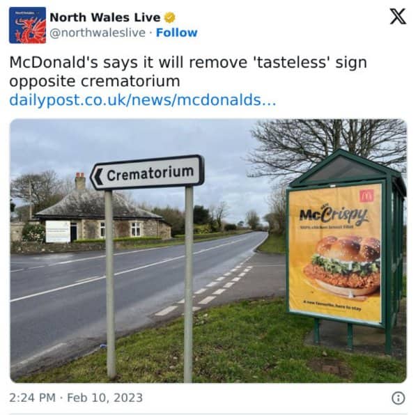 A crematorium road sign stands directly in front of a fast food bus shelter advert.