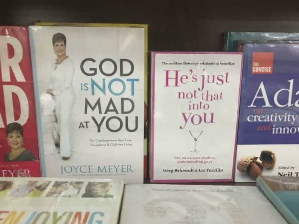 Bookstore shelf places a religious self help title directly beside a dating advice bestseller.
