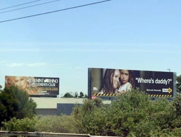 Roadside billboards place a gentlemen's club advert beside a workplace safety ad asking where's daddy.