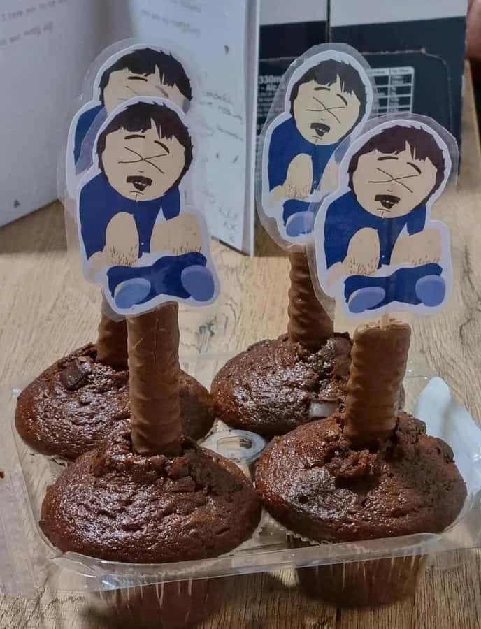 Muffins topped with cutout South Park figures of Randy Marsh on chocolate sticks.