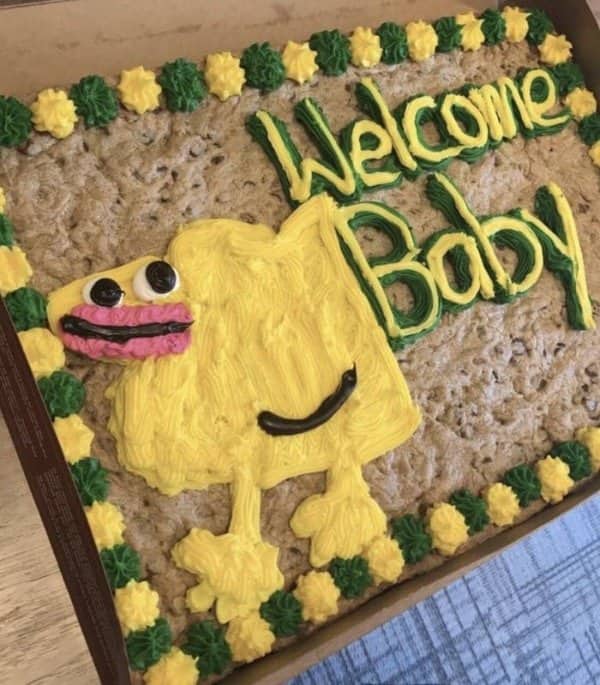 Giant cookie cake with a yellow piped creature and a green Welcome Baby message on top