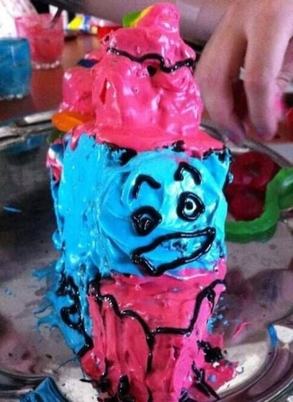 Blue and pink frosted cake decorated as a cartoon train face with smeared black outlines