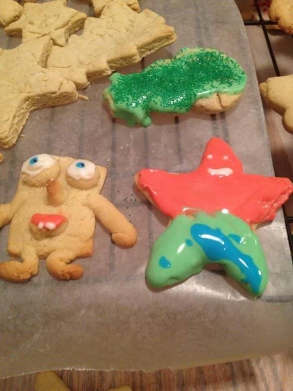 Sugar cookies decorated with runny icing including a lumpy person with wide mismatched eyes