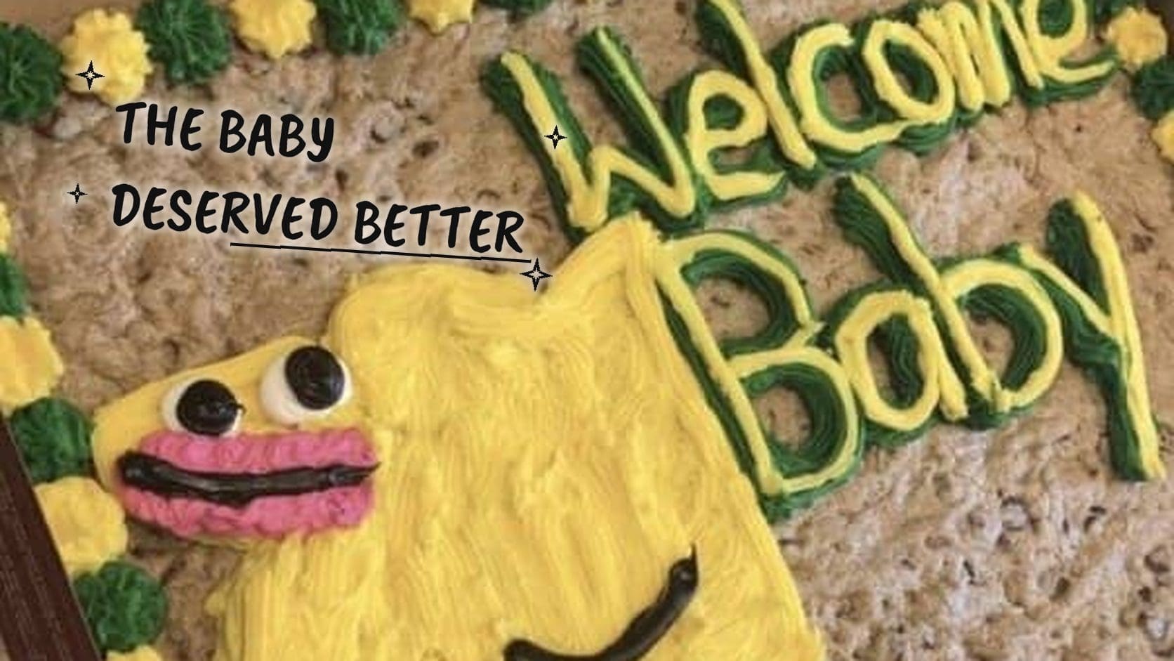 Giant cookie cake decorated with a lopsided yellow creature and a Welcome Baby message, a classic entry in cake fails