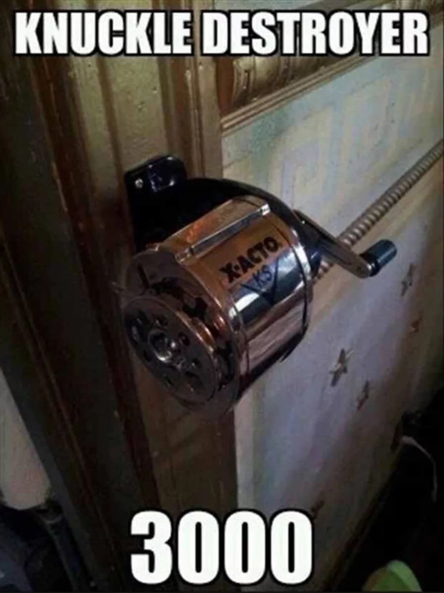 Wall-mounted manual pencil sharpener installed next to a door frame labeled as the 'Knuckle Destroyer 3000' in a classic meme.
