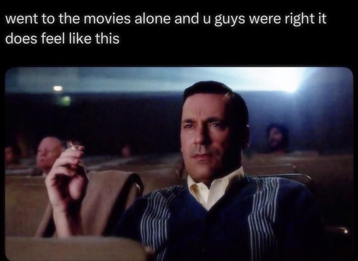 Don Draper smoking in a movie theater illustrating the dramatic feeling of going to cinema alone in an old meme.