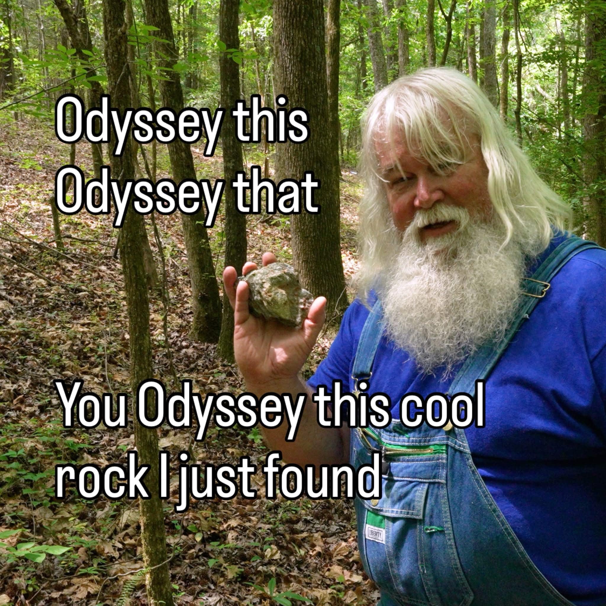Elderly bearded man in overalls proudly holding a rock in the woods punning on Homer's Odyssey in a classic meme.