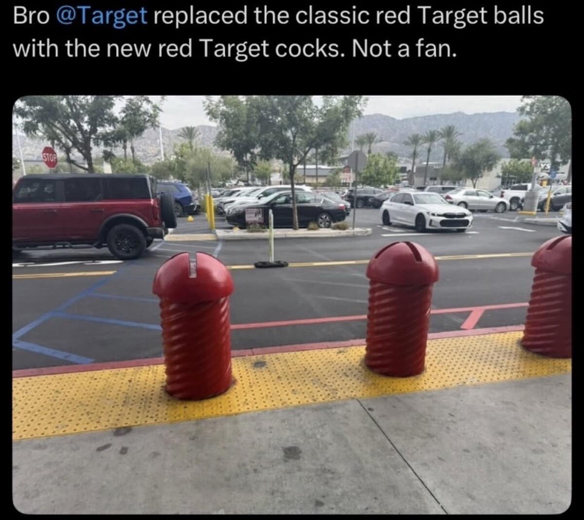 Red grooved cylindrical bollards outside a Target store parking lot, humorously criticized for replacing traditional spherical bollards in a classic meme.