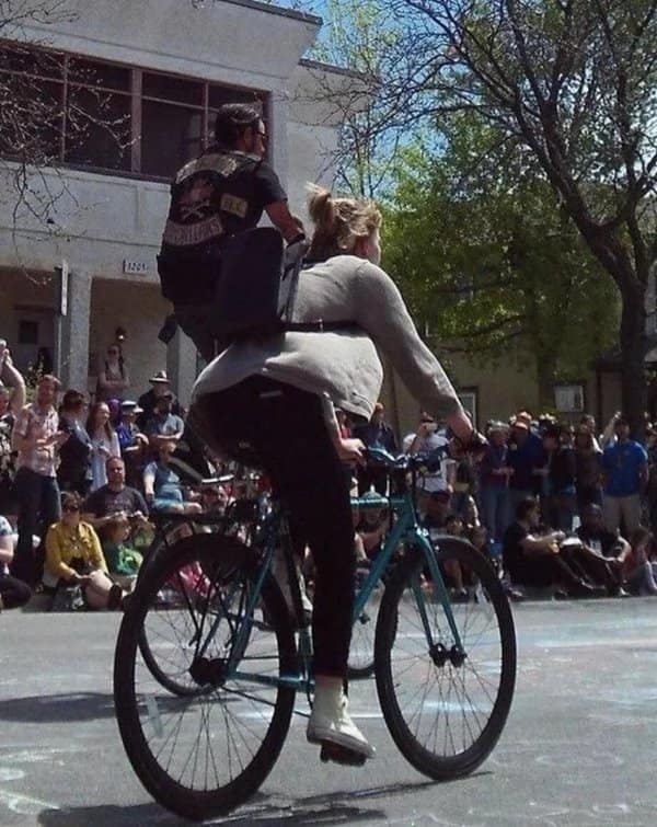 Cyclist whose legs seem to belong to the leather clad man riding behind her.