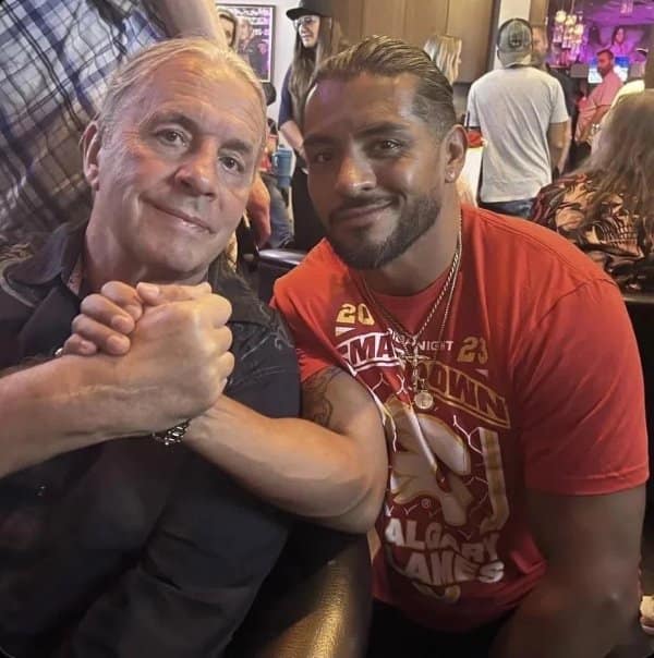 Two men clasping hands where their arms appear swapped between bodies.