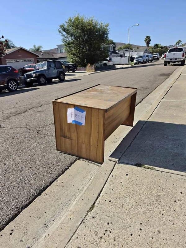 Wooden desk marked free on a curb, floating thanks to its shadow in confusing images.