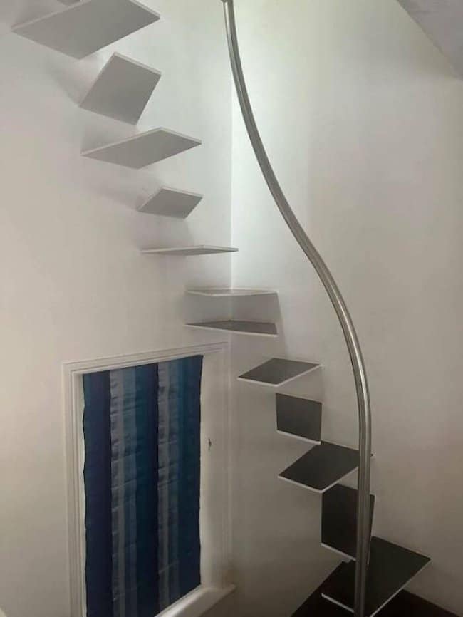 Floating white stairs curling past a doorway with a pole in the way.
