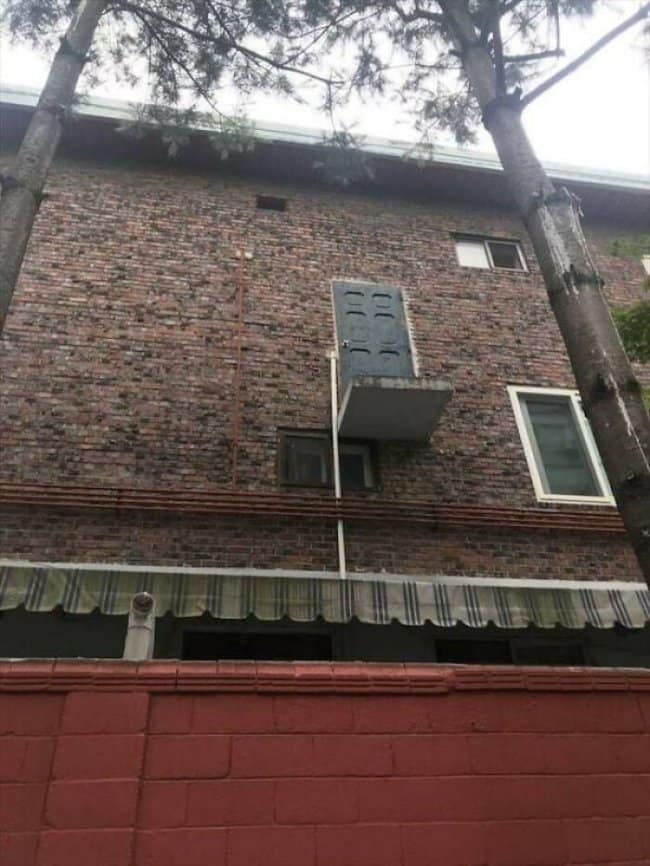 Brick apartment with a door opening onto a tiny ledge high above the ground.
