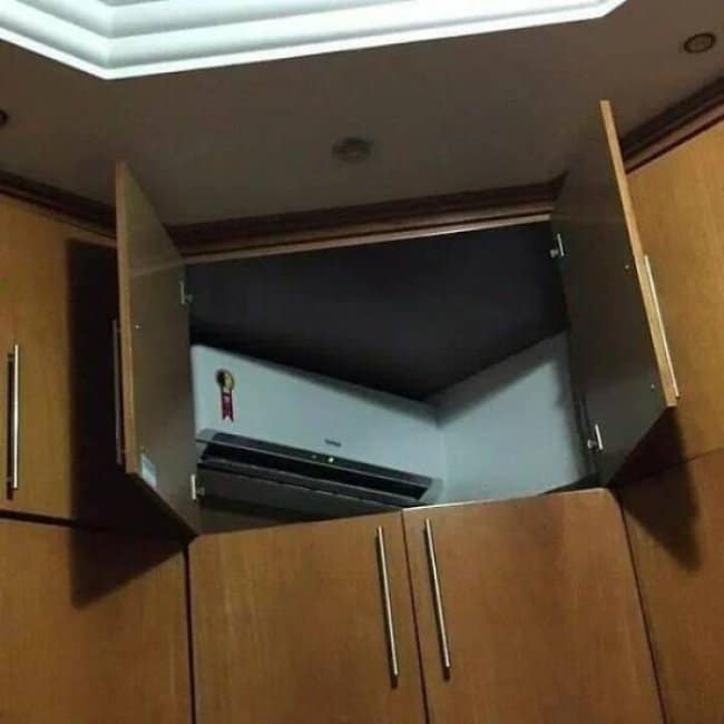 Kitchen cabinets built so they open straight onto an air conditioning unit.