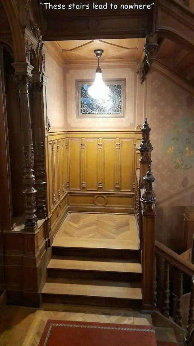 Ornate wooden Victorian staircase that ends at a paneled wall, labeled stairs to nowhere.