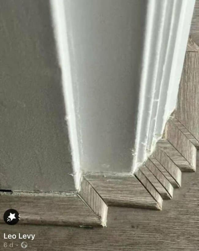 Baseboard trim cut in tiny jagged steps around a wall corner.