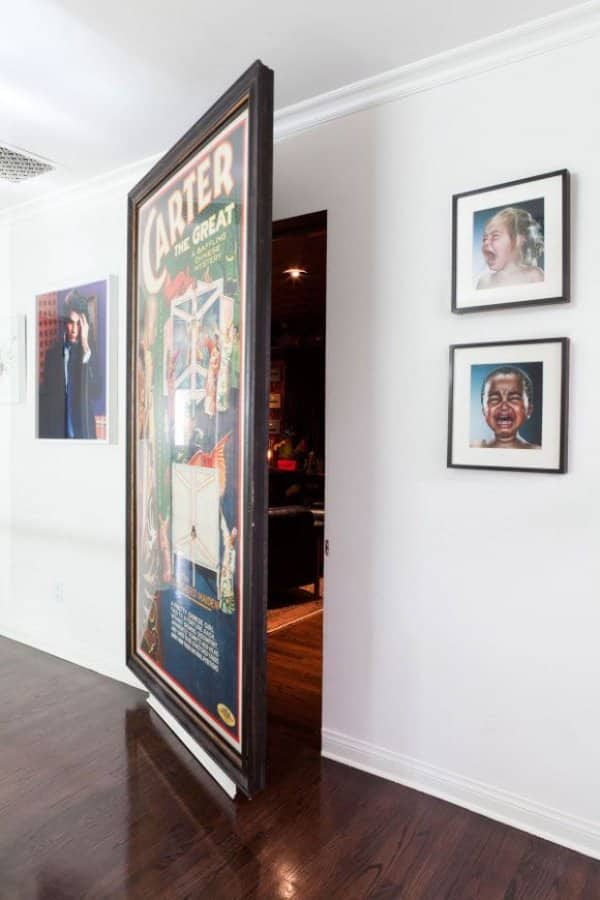 Framed magician poster swinging open as a hidden door into a dark wood paneled room