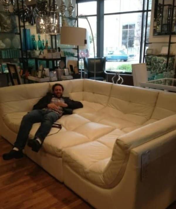 Man lying on an enormous cream sectional couch roughly the size of a small bedroom