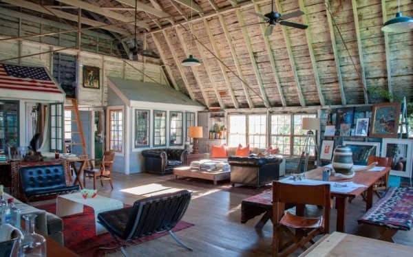 Converted barn loft with a vaulted wooden ceiling, leather chairs, an American flag and a long table