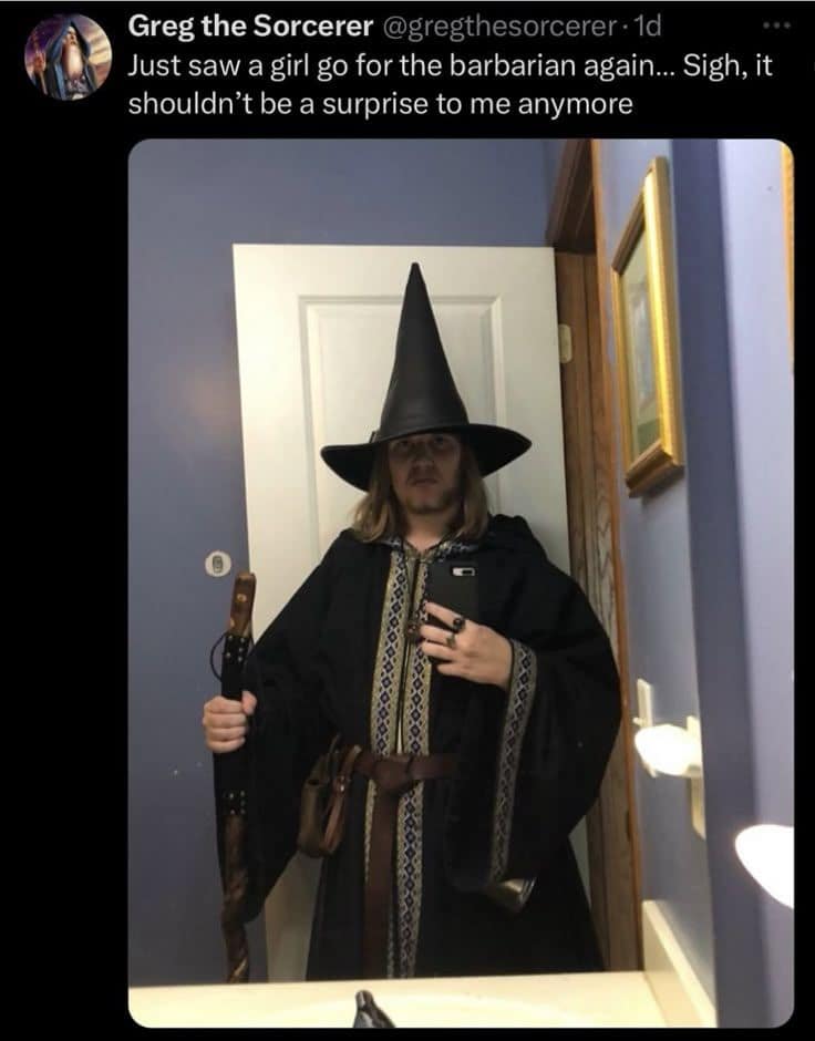 Cosplayer in a pointy wizard hat taking a bathroom mirror selfie, tweeting as Greg the Sorcerer complaining about girls choosing the Barbarian in a dnd meme.