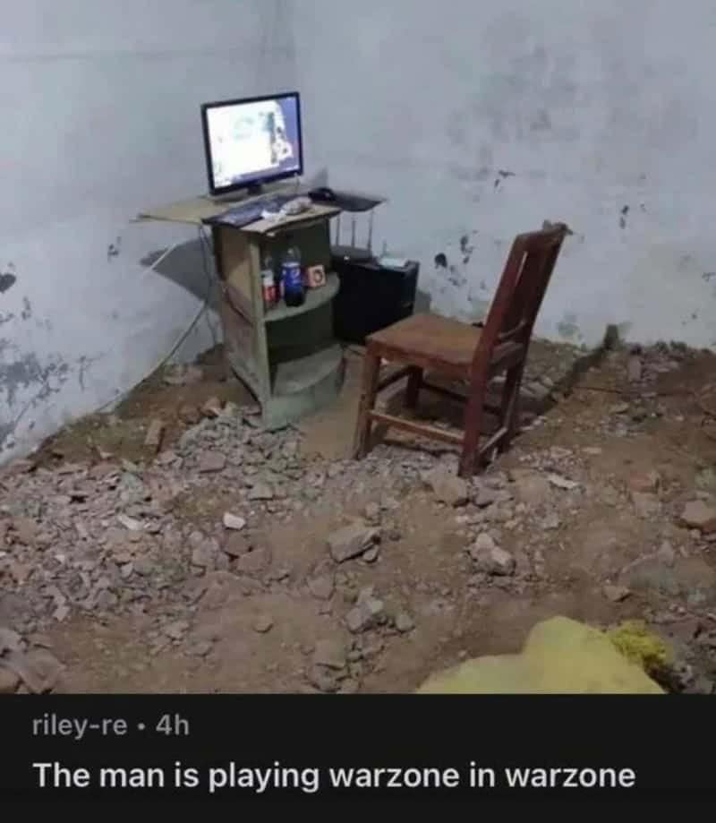 PC gaming setup placed inside a destroyed concrete room filled with dirt and rubble paired with a funny comment about playing Warzone in an active warzone.