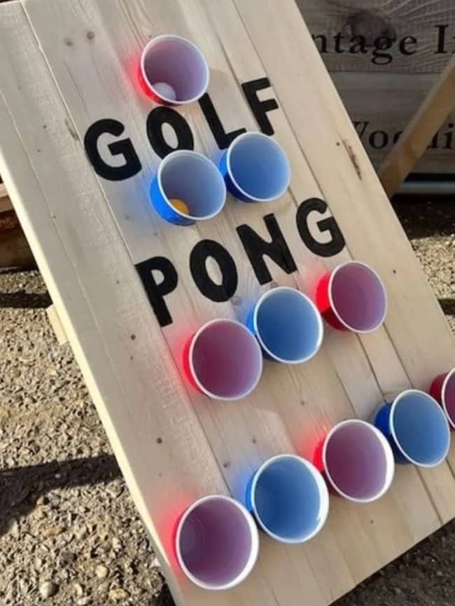 A wooden cornhole board with plastic cups for playing Golf Pong funny drinking games.