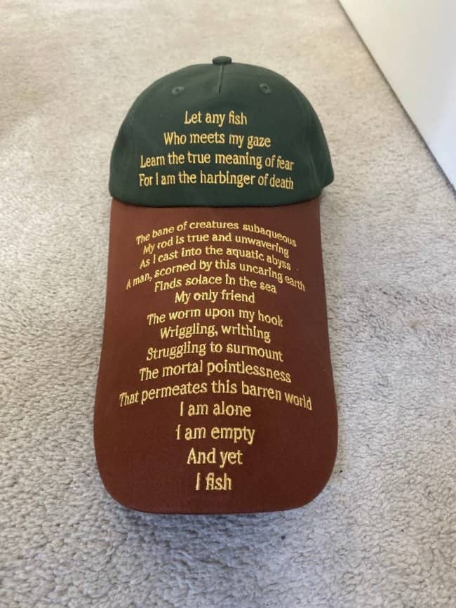 Green and brown baseball cap featuring an absurdly long, dramatic poem about fishing printed on the front brim.