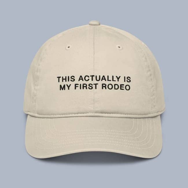 Light beige baseball hat printed with the honest phrase This actually is my first rodeo.