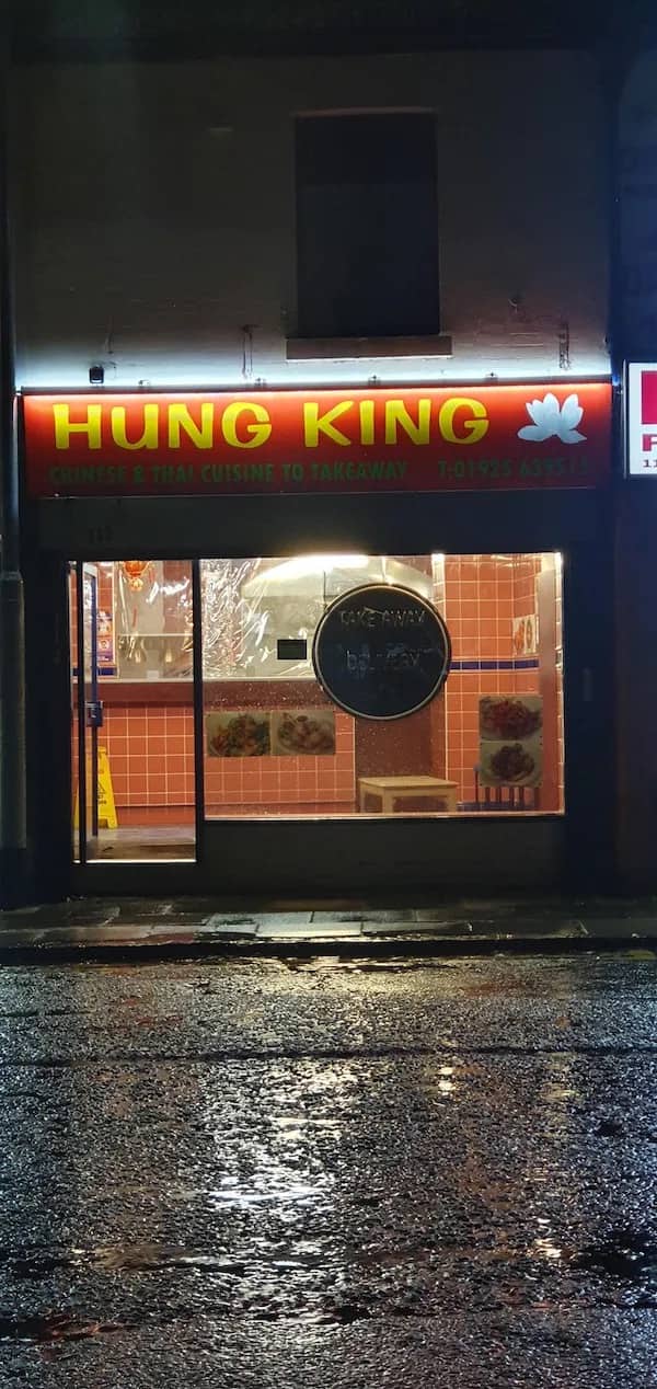Illuminated red sign of Chinese and Thai takeaway restaurant named Hung King at night.