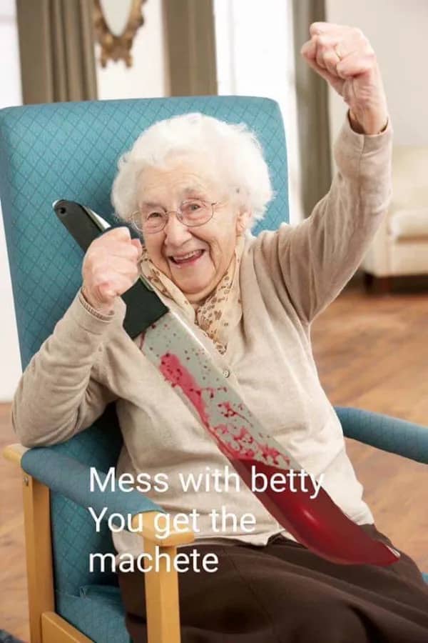 Smiling elderly woman holding a large bloody machete with funny threatening text.