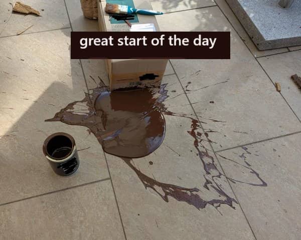 Large puddle of brown paint spilled across a clean tile patio causing a bad day.