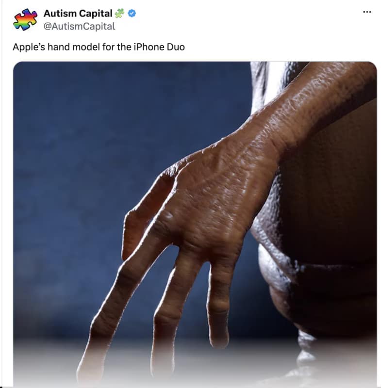 E.T.'s long, alien hand close-up labeled as the official Apple hand model required to reach across the massive unfolded iPhone Duo screen in an iphone duo meme.