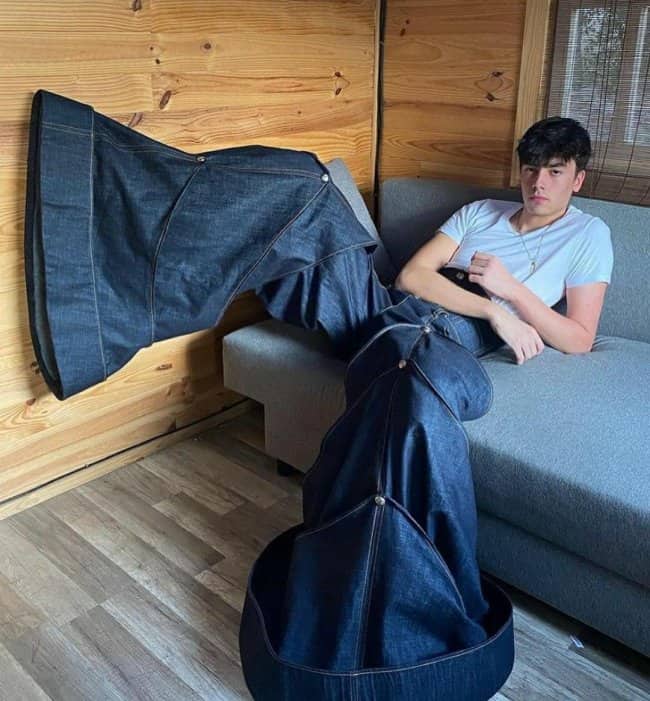 Young man sitting on couch wearing enormously wide bell bottom denim jeans memes.