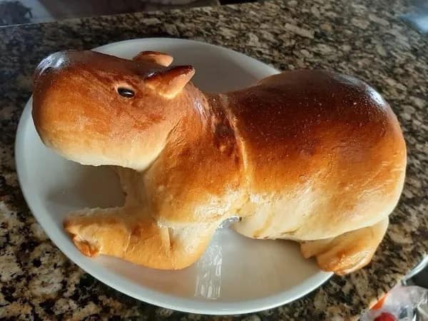 Photo of a golden-baked loaf of artisanal bread shaped like a capybara resting on a plate in a meme dump.