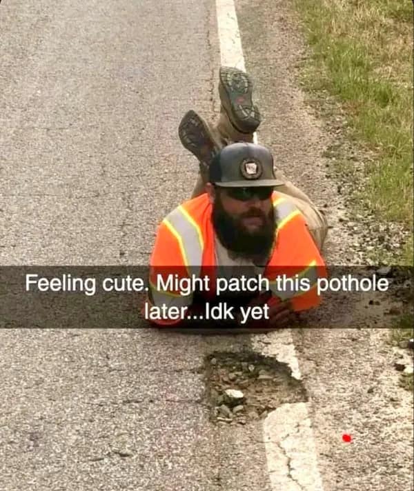 Road construction worker in high-vis gear posing seductively on asphalt next to a pothole in a meme dump.