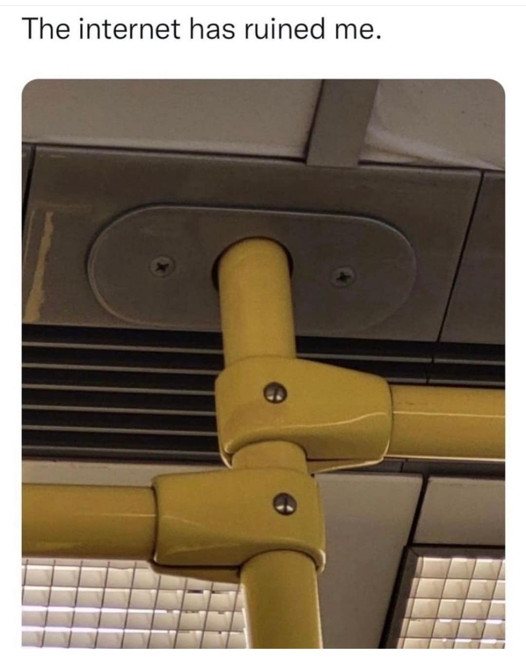 Close-up of yellow subway handrails mounted to a ceiling fixture that resembles an unintended suggestive or meme shape in a meme dump.