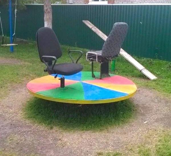 An office-themed playground merry-go-round equipped with swivel desk chairs in a meme dump.