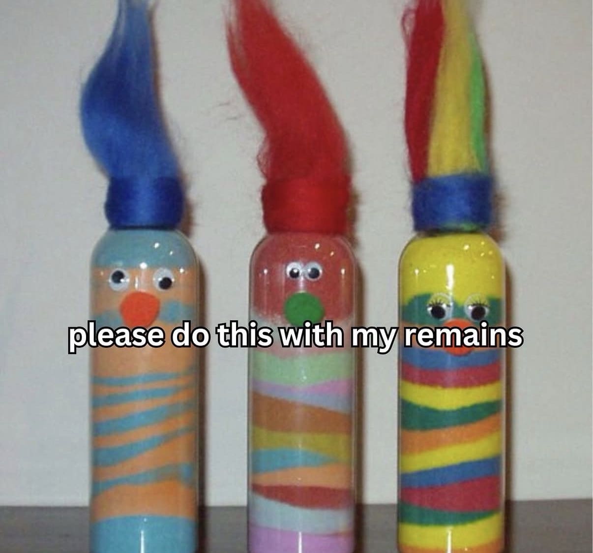 Three decorative glass jars filled with colorful layered sand art styled like troll dolls with googly eyes for a funeral request in a funny memes post.
