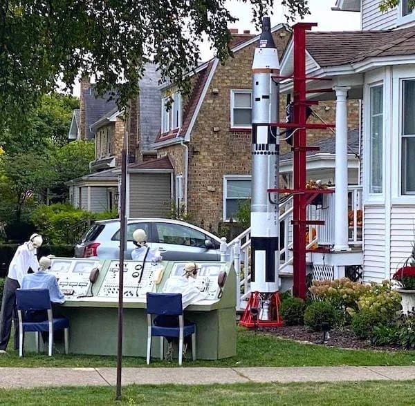 Elaborate suburban front yard Halloween display featuring skeletons staffing a NASA rocket launch control console in a hilarious memes photo.
