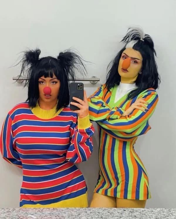 Two women in striped sweaters doing a Bert and Ernie cosplay mirror selfie.