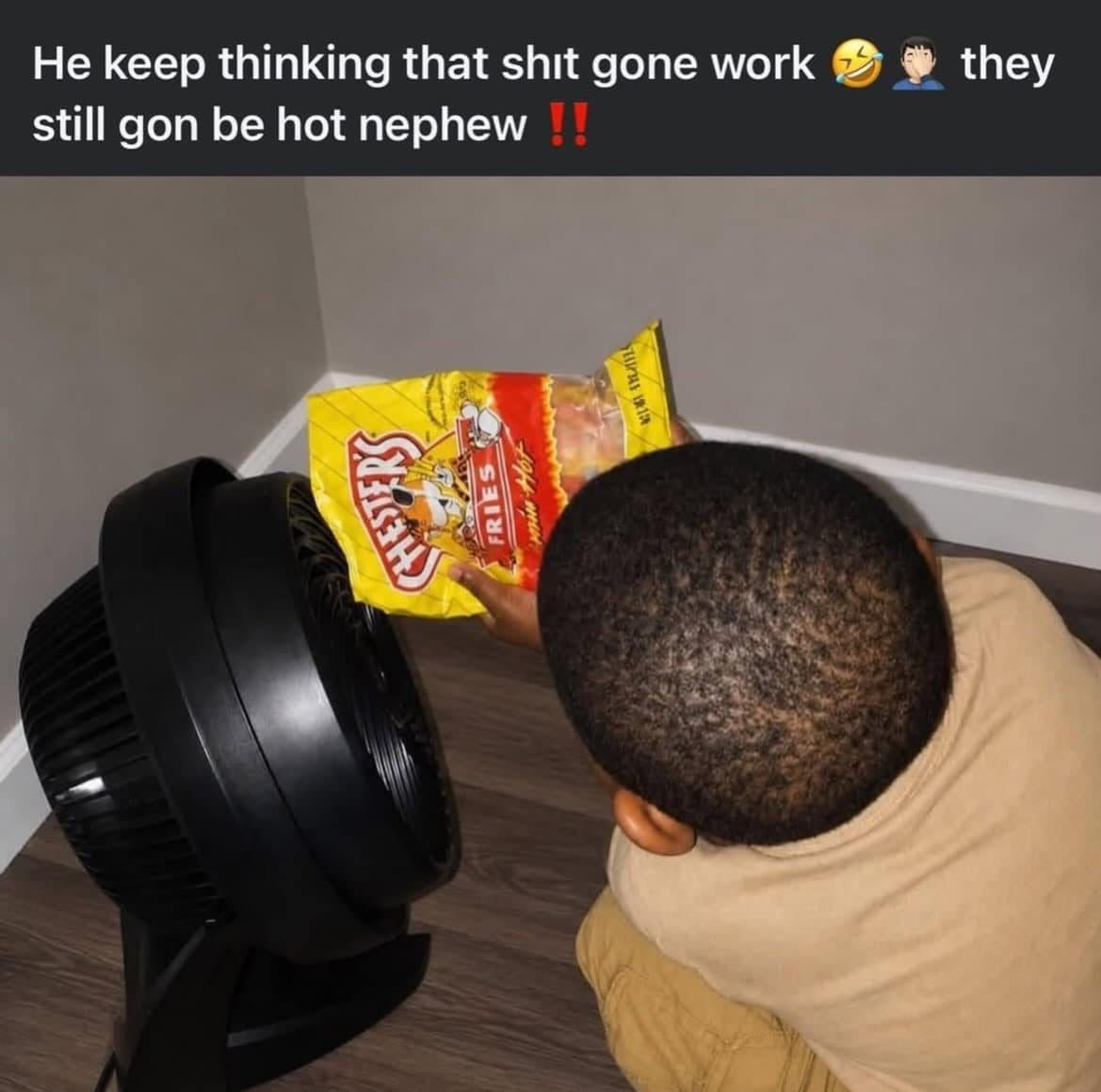 Kid holding a bag of spicy chips up to a fan to cool them down.