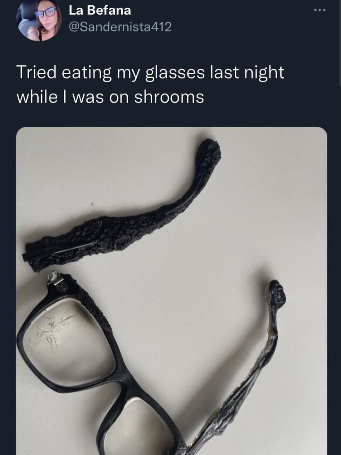 Completely chewed and crushed black plastic glasses frames posted with a tweet about trying to eat them on shrooms in a meme dump.