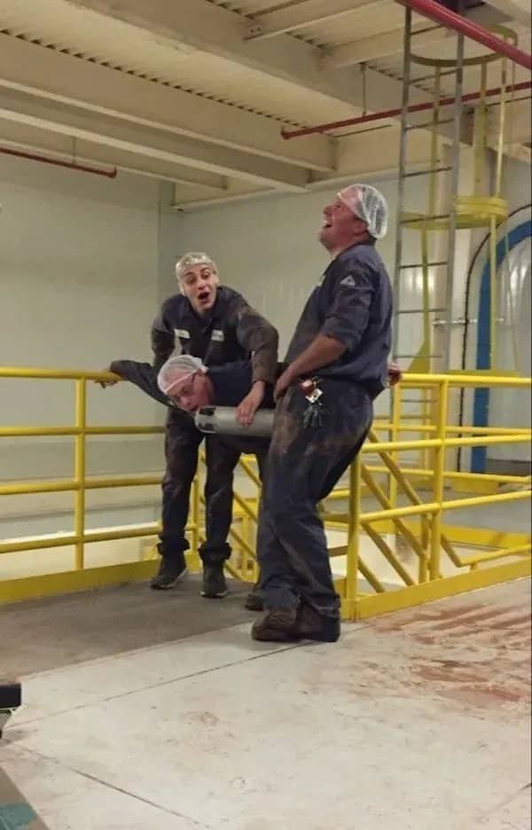 Factory workers fooling around and pulling a prank with equipment funny workplace humor meme.