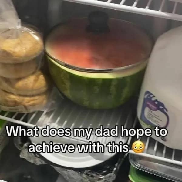 Half a watermelon covered with a pot lid sitting inside a crowded refrigerator