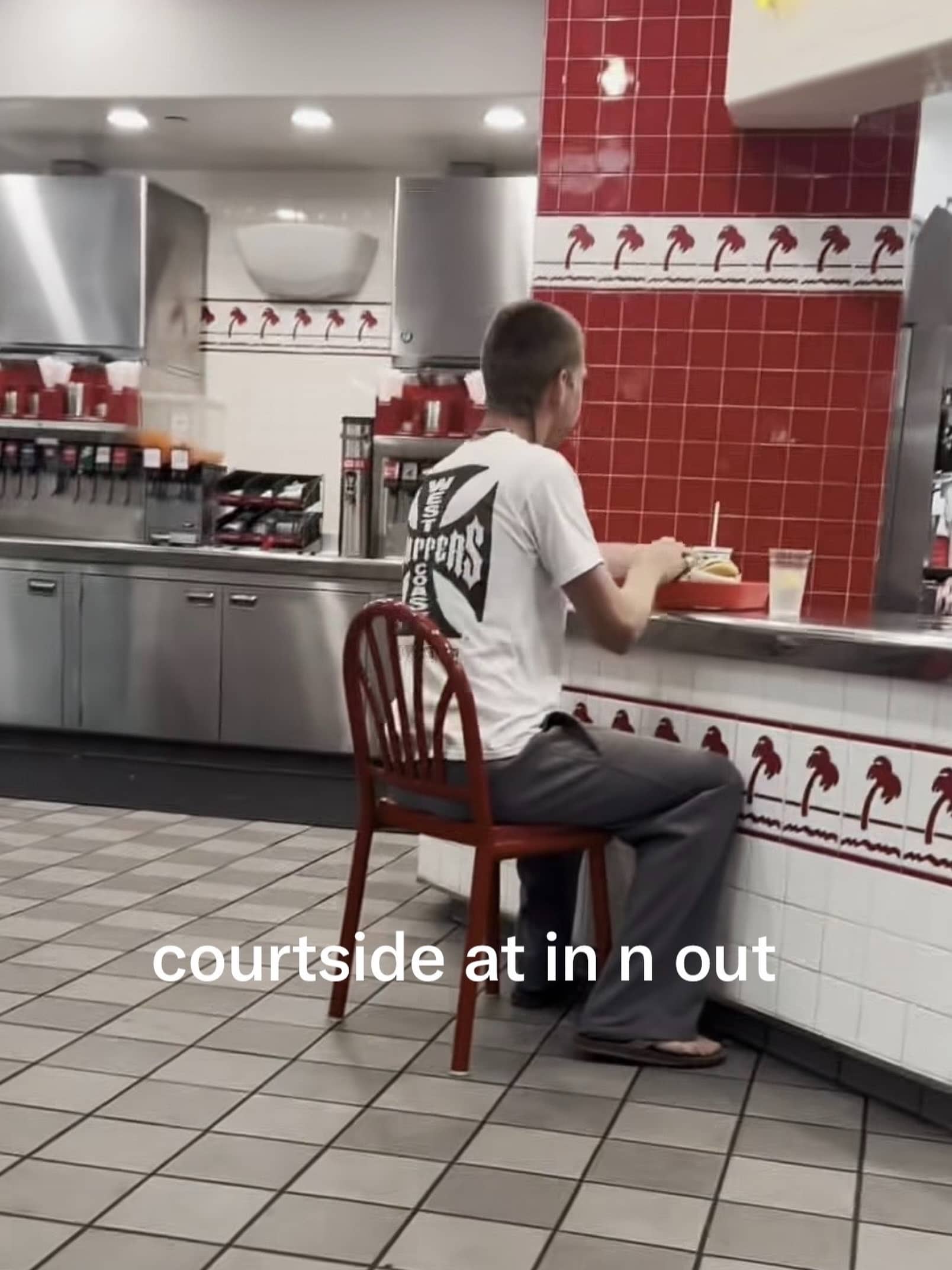 Funny photo of a man sitting on a dining chair inside In-N-Out.