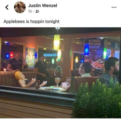 Blow-up mannequin sitting in a booth inside a restaurant labeled Applebees is hoppin tonight.