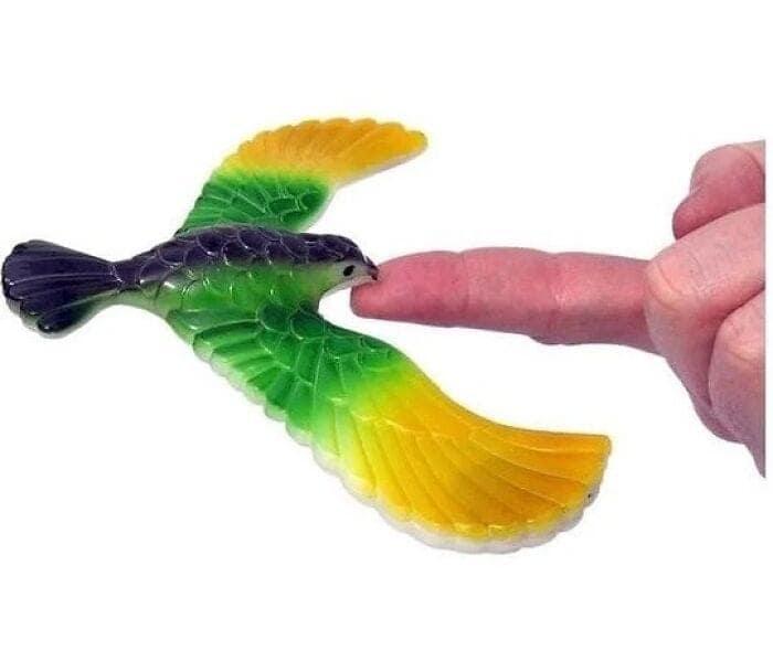 Classic plastic balancing eagle toy miraculously balancing by its beak on a finger tip in nostalgic images.
