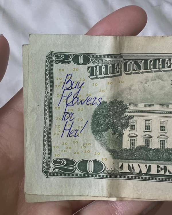 Twenty dollar bill with handwritten note saying buy flowers for her